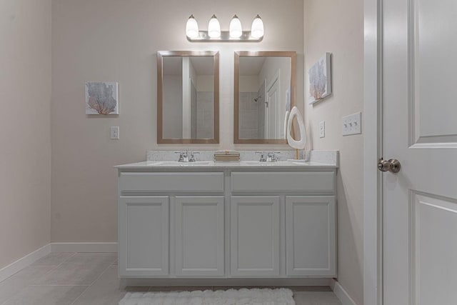 bathroom featuring baseboards, double vanity, a sink, and tile patterned floors