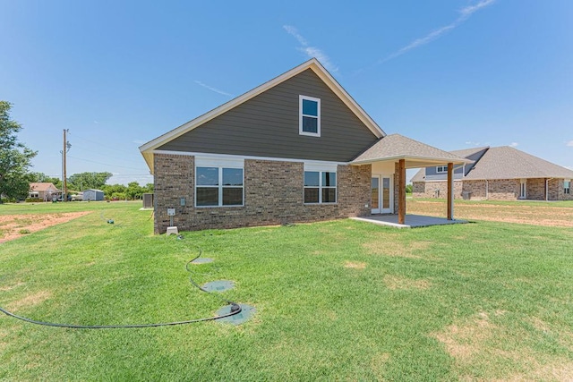 rear view of property with a patio area, brick siding, and a yard