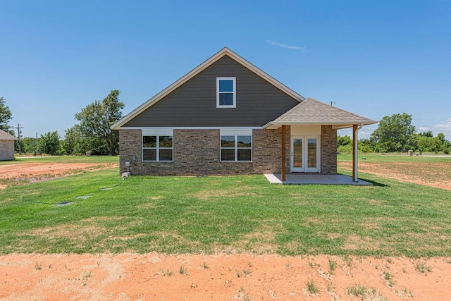 rear view of property with a patio area, a lawn, and brick siding