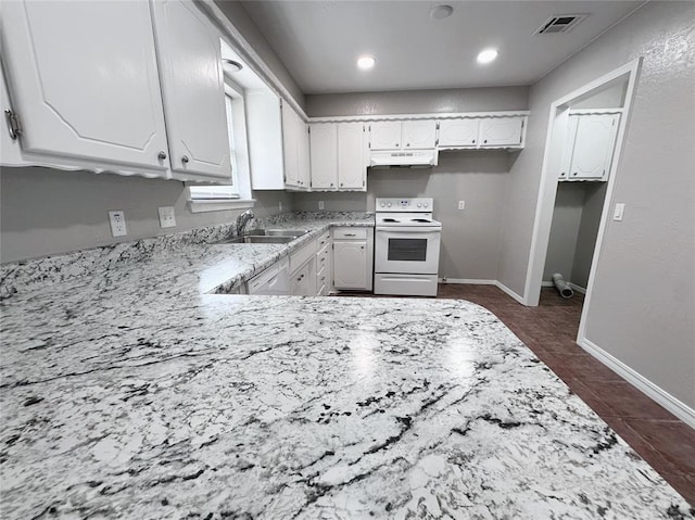 kitchen with white electric range oven, sink, light stone counters, dark tile patterned floors, and white cabinets