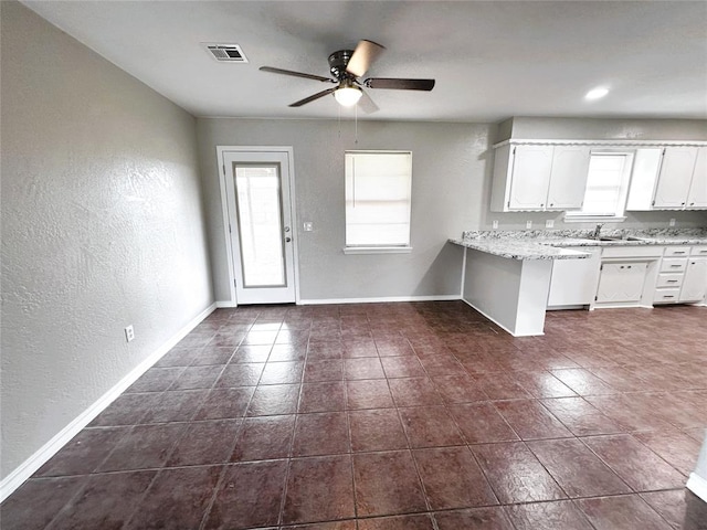 kitchen featuring sink, dark tile patterned floors, ceiling fan, white cabinetry, and light stone countertops