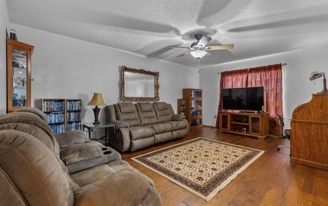 living room featuring ceiling fan, dark hardwood / wood-style floors, and a textured ceiling