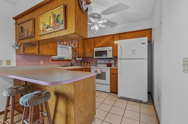 kitchen with light tile patterned floors, white appliances, a kitchen breakfast bar, and kitchen peninsula