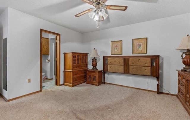 bedroom with ceiling fan, light colored carpet, and ensuite bath