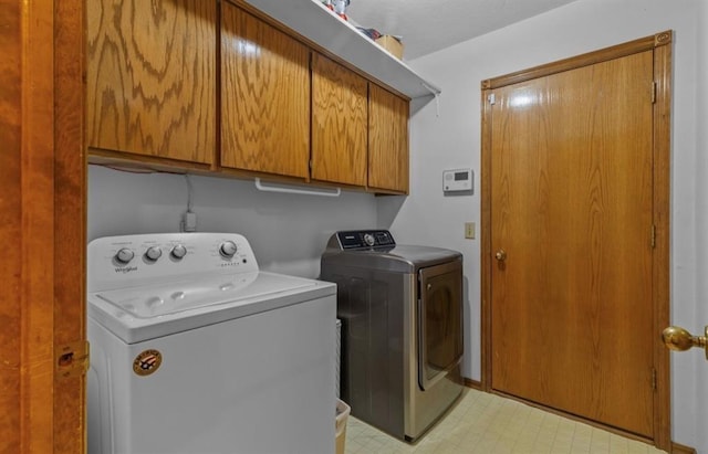 clothes washing area with washing machine and dryer and cabinets