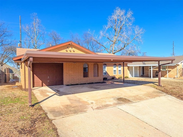 ranch-style home featuring brick siding, fence, a chimney, a carport, and driveway