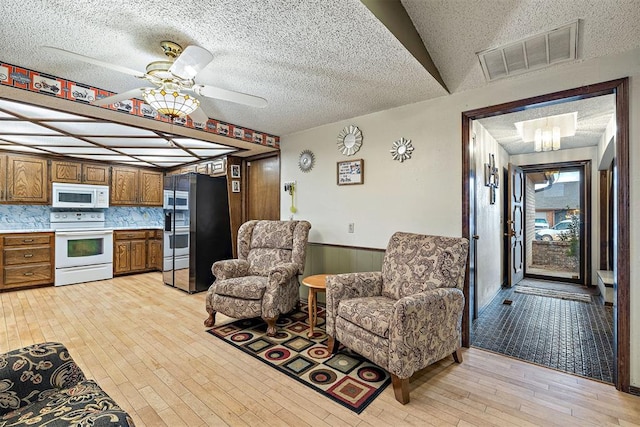 interior space featuring ceiling fan, a textured ceiling, and light hardwood / wood-style floors