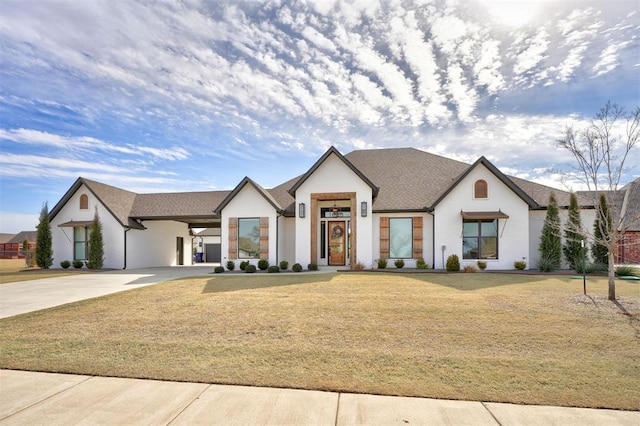 modern farmhouse style home featuring a carport, a front yard, concrete driveway, and stucco siding