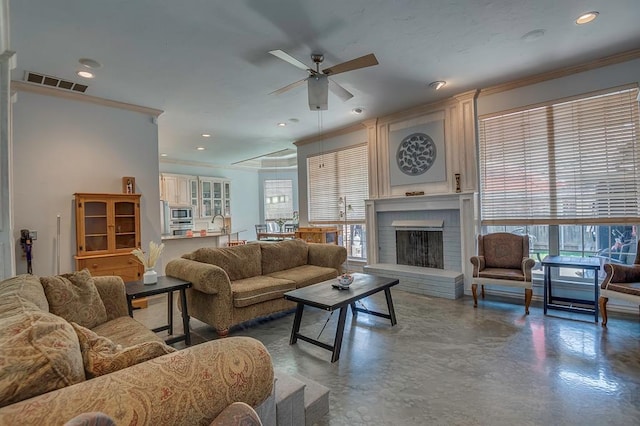 living room featuring a brick fireplace, ornamental molding, concrete floors, and ceiling fan