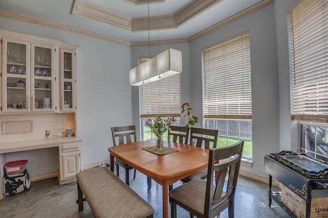 dining area featuring crown molding, a tray ceiling, and built in desk