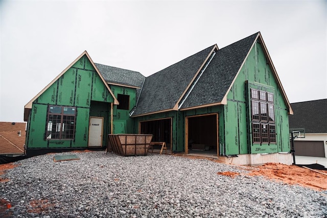 property under construction featuring roof with shingles and a garage