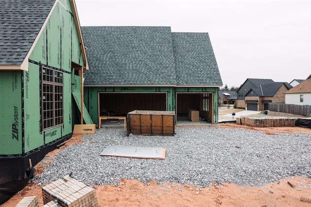 view of side of home with roof with shingles
