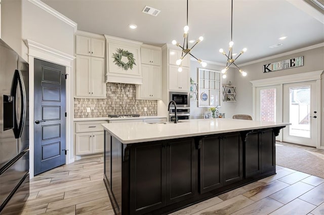 kitchen with a notable chandelier, tasteful backsplash, stainless steel appliances, white cabinets, and light countertops