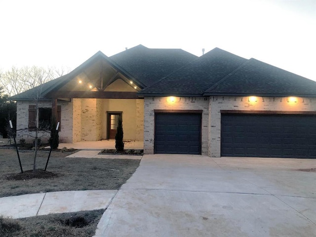 view of front of house featuring a garage, concrete driveway, and a shingled roof