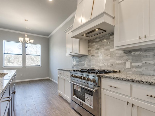 817 Carrie Ct, Purcell, OK 73080 - kitchen with a notable chandelier, ornamental molding, custom range hood, high end stainless steel range oven, and tasteful backsplash