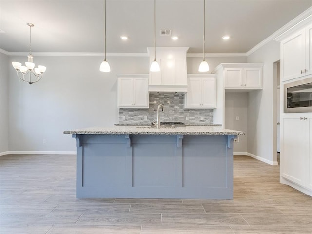 817 Carrie Ct, Purcell, OK 73080 - kitchen featuring visible vents, a breakfast bar, white cabinets, stainless steel microwave, and tasteful backsplash