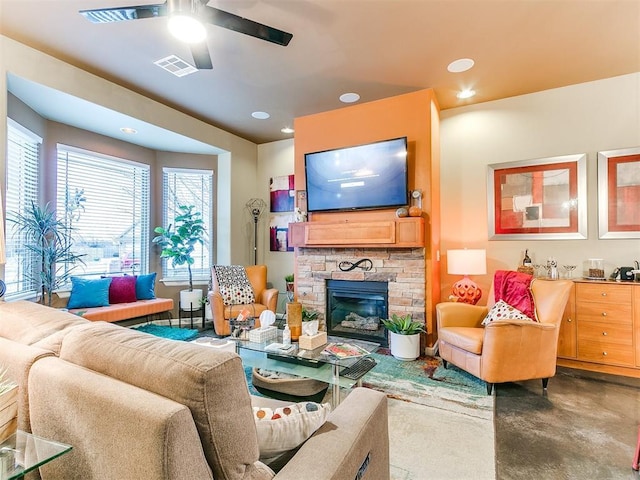 living room with ceiling fan, a fireplace, and concrete flooring