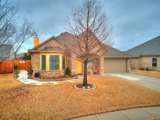 view of front facade featuring fence, an attached garage, a chimney, concrete driveway, and brick siding