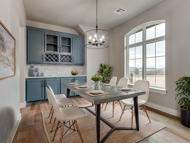 3134 NW 37th St, Newcastle, OK 73065 - dining area featuring light wood-style floors, a chandelier, baseboards, a dry bar, and a water view