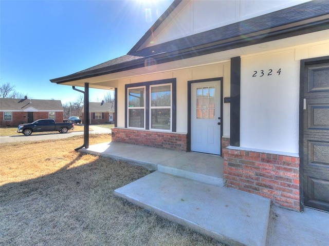 entrance to property with covered porch and brick siding