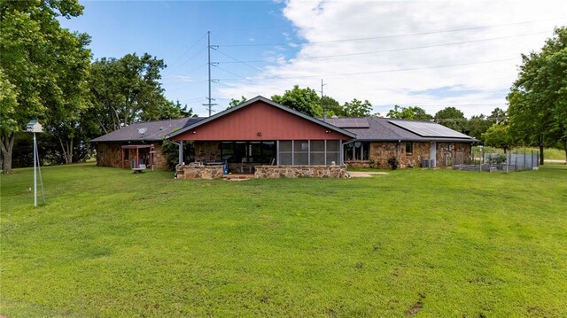 1901 E 15th St, Chandler, OK 74834 - rear view of property with solar panels, stone siding, a lawn, and a sunroom
