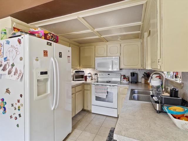 kitchen featuring sink, white appliances, cream cabinetry, and light tile patterned flooring