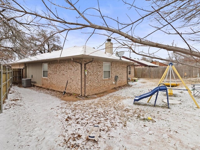 snow covered property with a playground and cooling unit