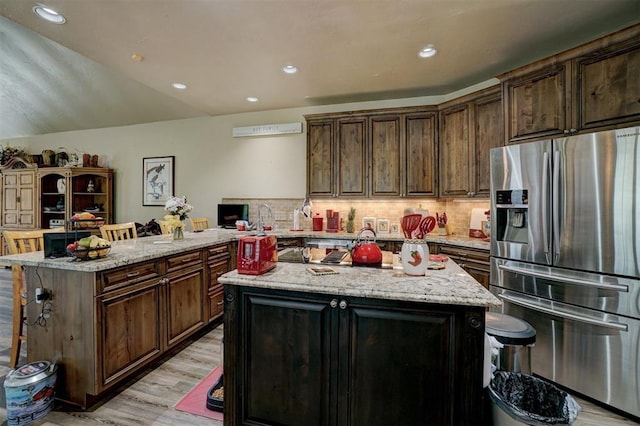 kitchen featuring decorative backsplash, a kitchen island, stainless steel fridge, and kitchen peninsula