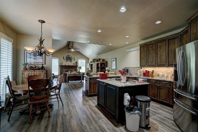 kitchen with stainless steel fridge, plenty of natural light, dark brown cabinetry, a kitchen island, and decorative light fixtures