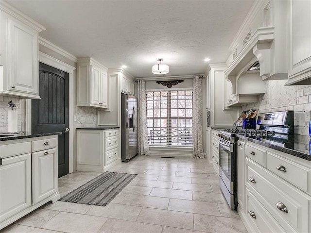 kitchen featuring white cabinetry, decorative backsplash, stainless steel appliances, and dark stone counters