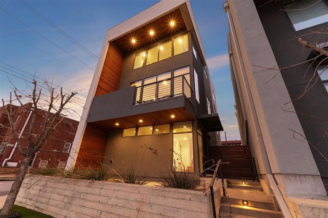 contemporary home featuring a balcony and stucco siding