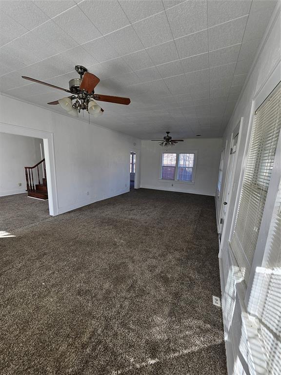 unfurnished living room with dark carpet and ceiling fan