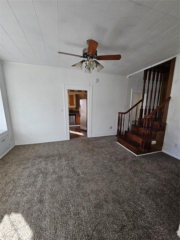 unfurnished living room with ceiling fan, a textured ceiling, and dark carpet