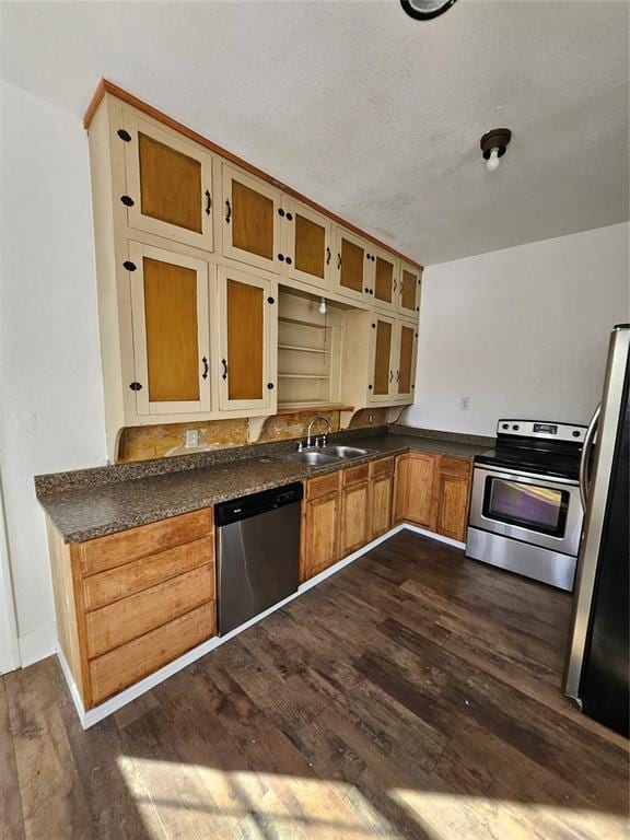 kitchen with appliances with stainless steel finishes, sink, a textured ceiling, and dark hardwood / wood-style flooring