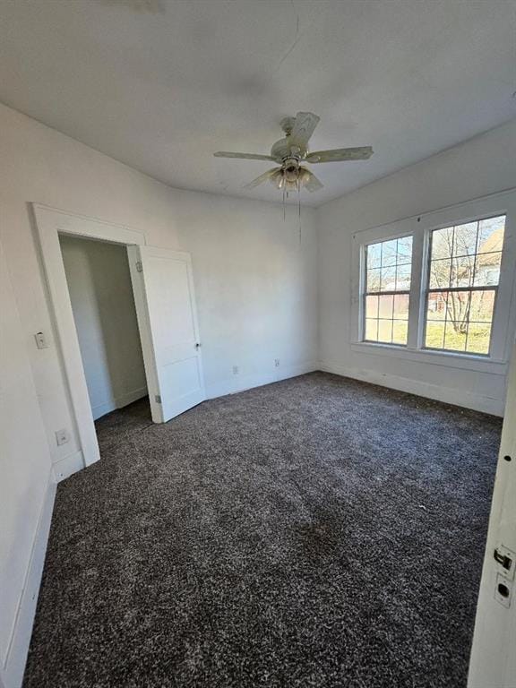 unfurnished bedroom with ceiling fan and dark carpet