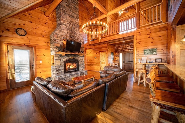 living room with an inviting chandelier, a stone fireplace, and wood walls