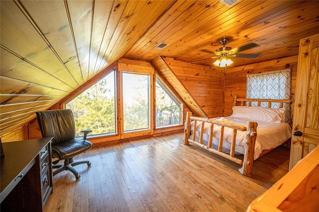 bedroom with vaulted ceiling, wooden ceiling, wood walls, and light wood-type flooring