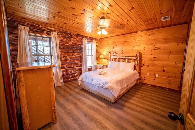 bedroom with log walls, wood-type flooring, and wooden ceiling