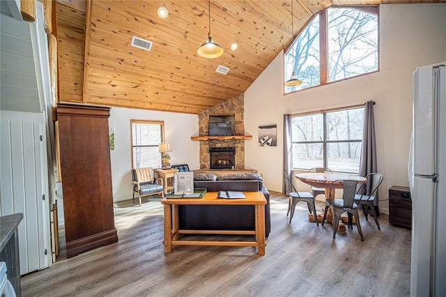 living room featuring wood ceiling, a stone fireplace, high vaulted ceiling, and hardwood / wood-style flooring