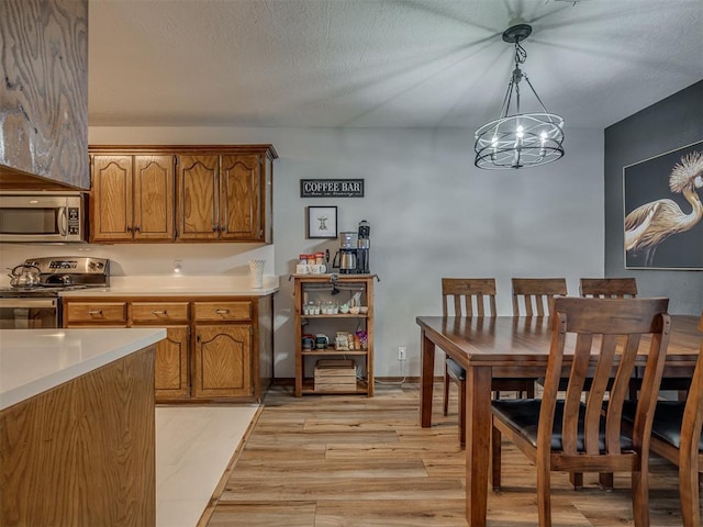 2108 Barton St Unit 2110, Norman, OK 73072 - dining space featuring light wood-type flooring, a notable chandelier, and a textured ceiling