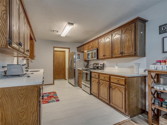 2108 Barton St Unit 2110, Norman, OK 73072 - kitchen featuring a textured ceiling, visible vents, light countertops, a sink, and stainless steel appliances