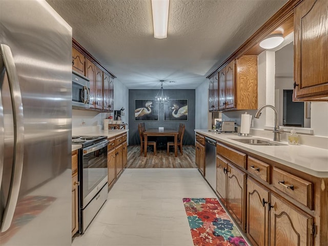 2108 Barton St Unit 2110, Norman, OK 73072 - kitchen with a notable chandelier, light countertops, a textured ceiling, appliances with stainless steel finishes, and a sink