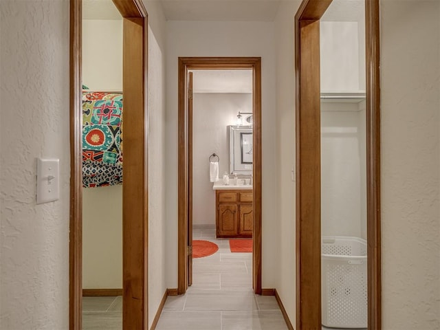 2108 Barton St Unit 2110, Norman, OK 73072 - hall featuring baseboards, a textured wall, a sink, and light tile patterned floors