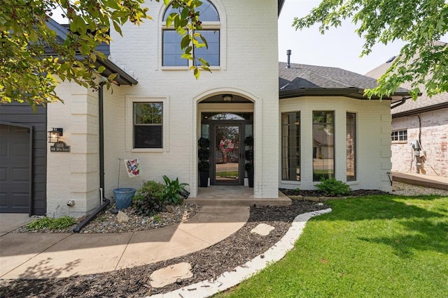 1408 NW 147th St, Edmond, OK 73013 - view of exterior entry with brick siding, a yard, and roof with shingles