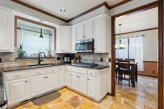 1408 NW 147th St, Edmond, OK 73013 - kitchen with appliances with stainless steel finishes, a chandelier, white cabinetry, ornamental molding, and decorative light fixtures