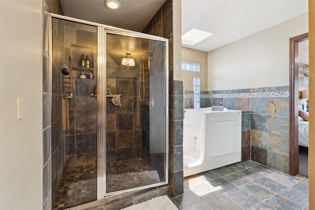 1408 NW 147th St, Edmond, OK 73013 - full bathroom with a skylight, tile walls, a stall shower, and a wainscoted wall