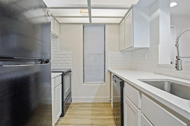 kitchen featuring tasteful backsplash, white cabinetry, sink, and black appliances