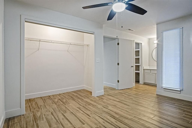 unfurnished bedroom with ensuite bath, light hardwood / wood-style floors, a closet, and ceiling fan