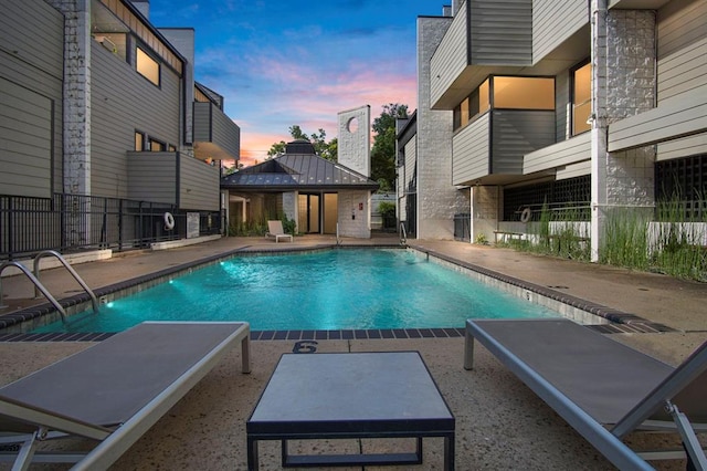 pool at dusk featuring a patio