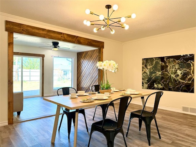 dining space featuring crown molding, wood-type flooring, a textured ceiling, and ceiling fan with notable chandelier